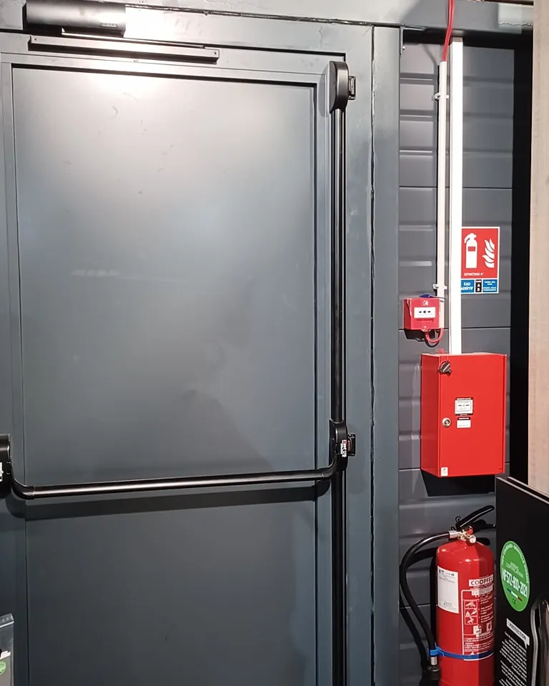 Déclencheur manuel d'alarme incendie et extincteur posés dans un local industriel