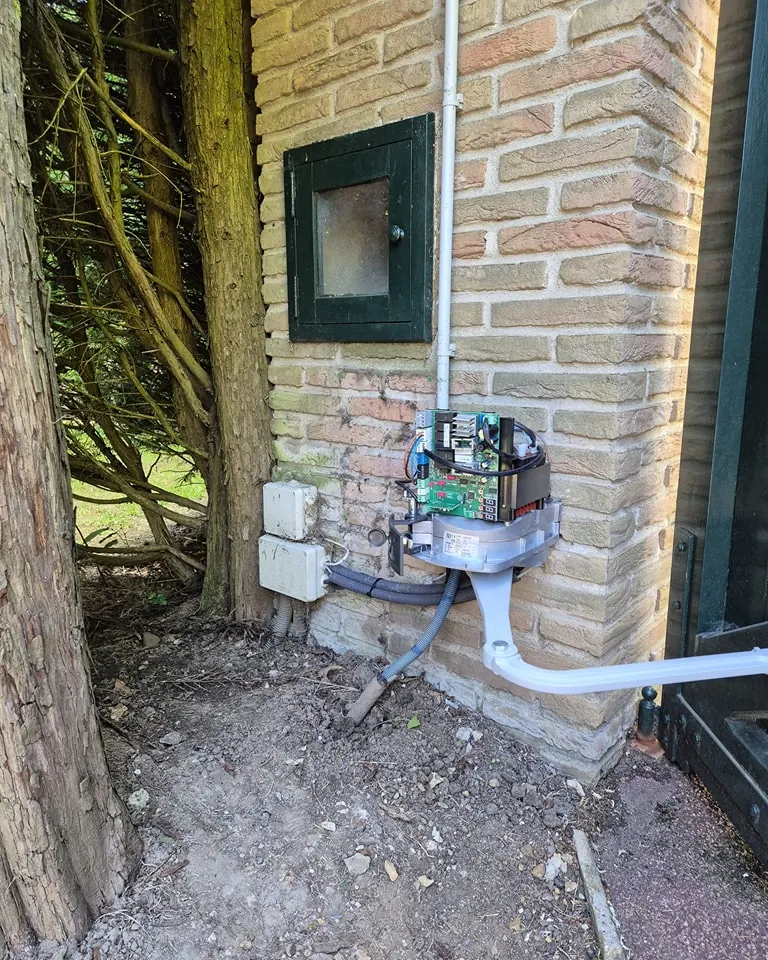 Coffret électrique et gaines posés sur un pilier en brique à l'extérieur