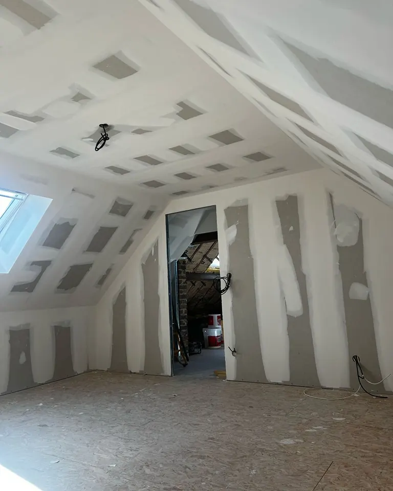 Combles aménagés vus depuis l'escalier : placo et bandes terminés