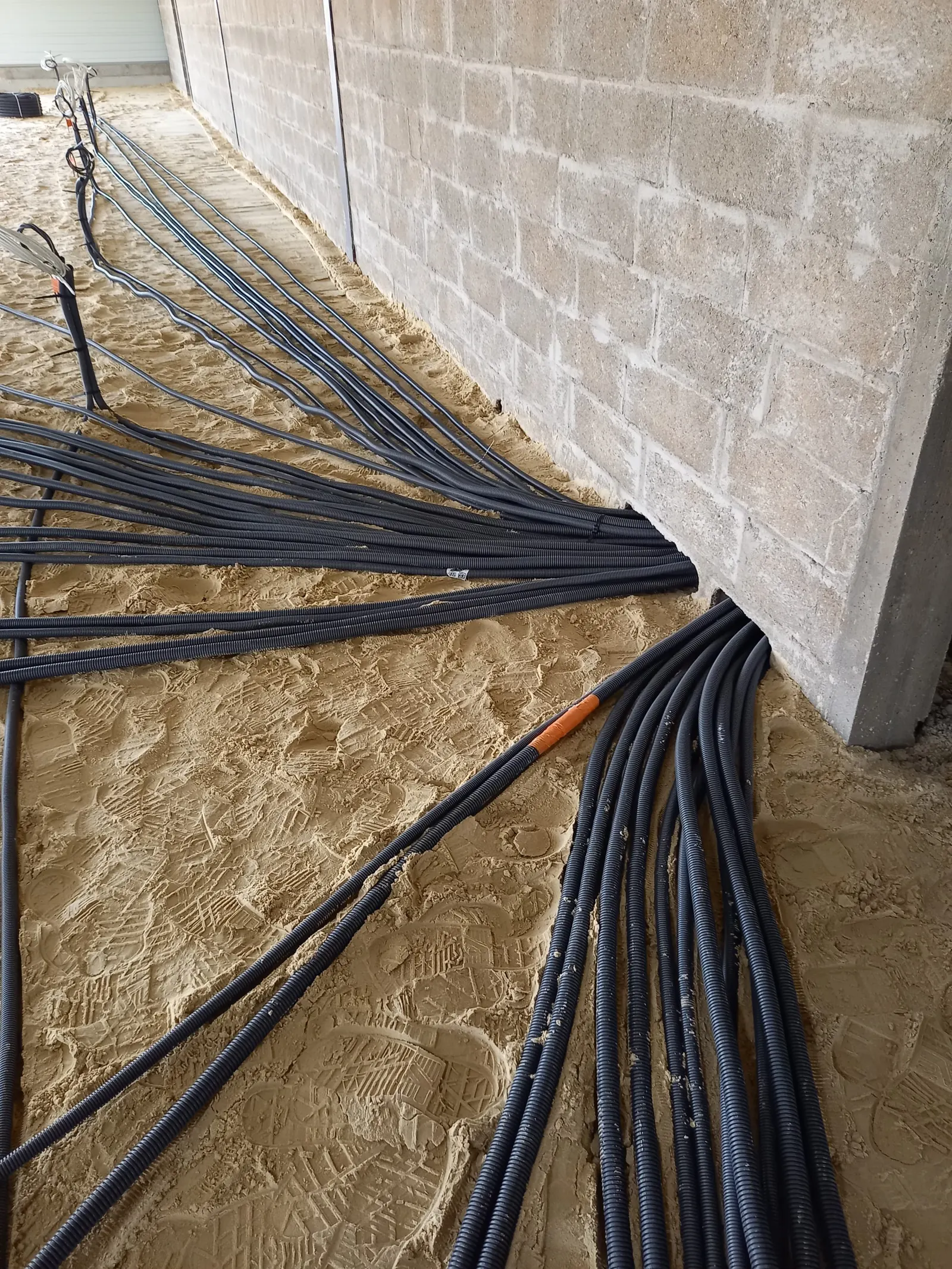 Gaines électriques regroupées le long d'un mur en parpaings avant dalle