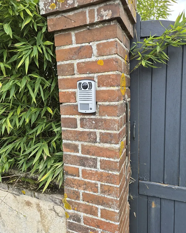 Platine d'interphone vidéo posée sur un pilier en brique