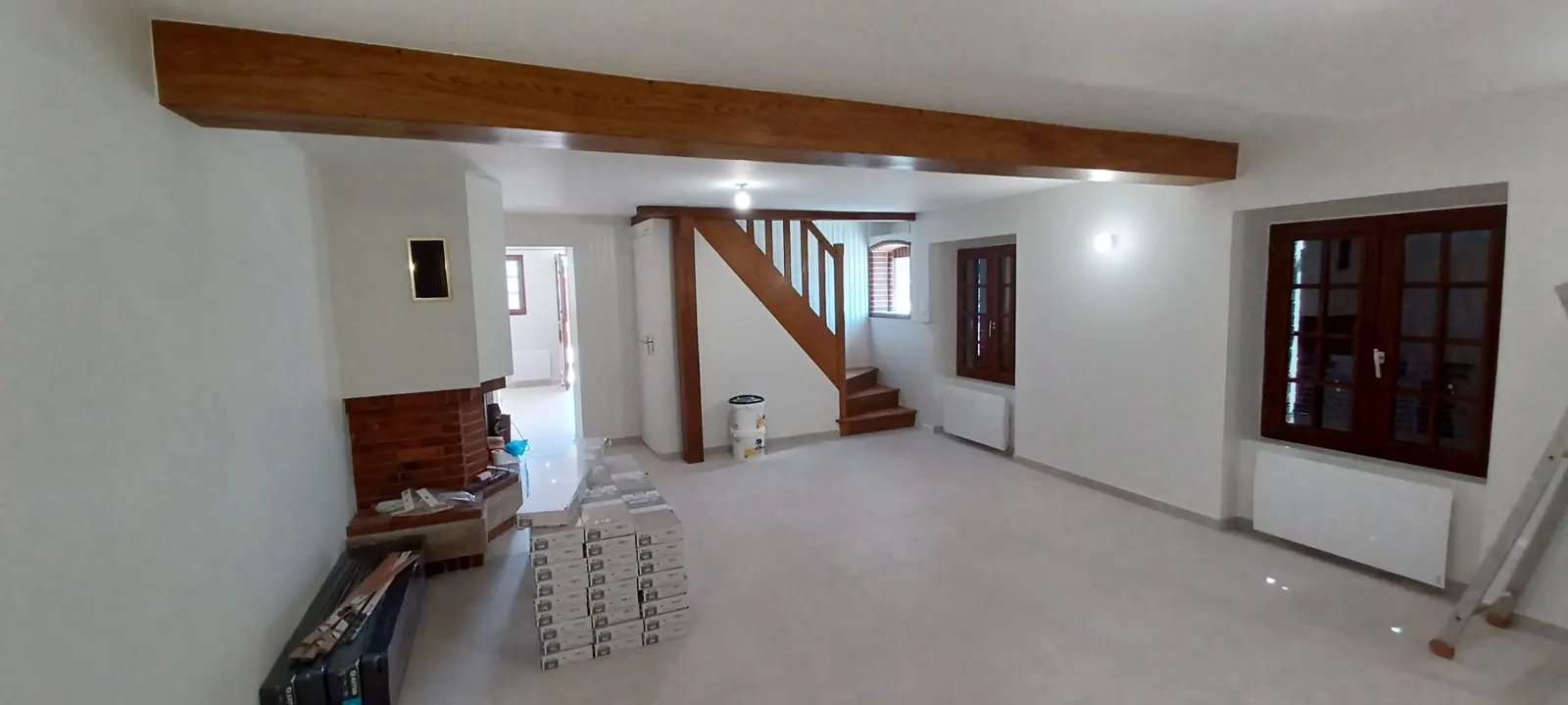Pièce à vivre rénovée : plafond en placo, poutre conservée, cheminée